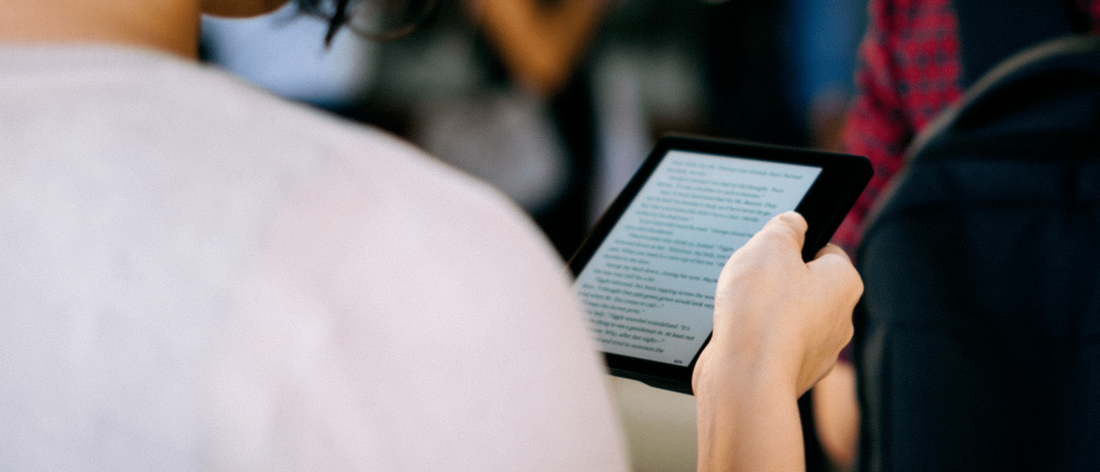 Como funciona uma biblioteca digital: fotografia de uma pessoa lendo um livro digital.