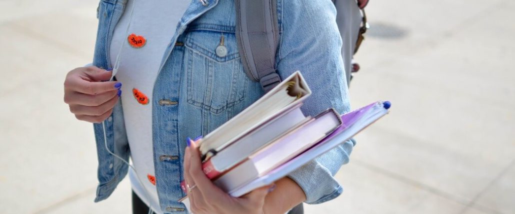 Retenção de alunos no ensino superior: fotografia de uma estudante segurando livros.