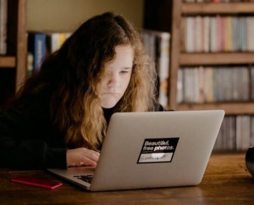 Tecnologia no ensino: fotografia de uma mulher usando o computador em uma biblioteca.