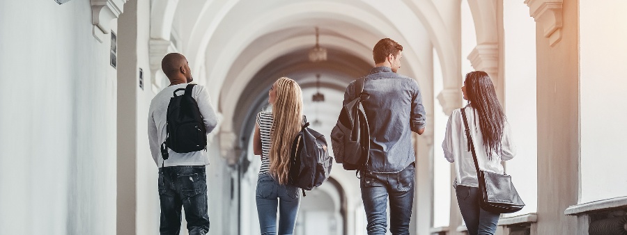 Plano de internacionalização Universidade: fotografia de 4 estudantes universitários andando pelo corredor de uma instituição de ensino superior.