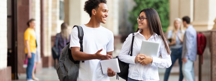 Financiamento estudantil privado: fotografia de dois estudantes andando e conversando nos corredores de uma instituição de educação superior.