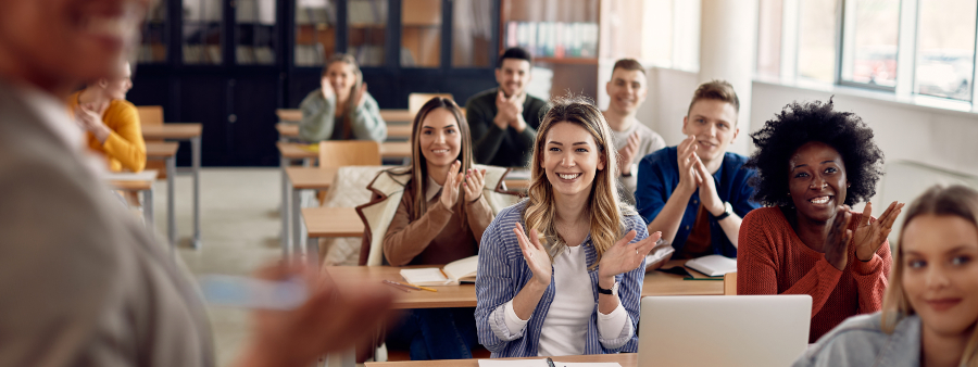 Gestão acadêmica: fotografia de uma sala de aula com alunos sorridentes e batendo palmas.