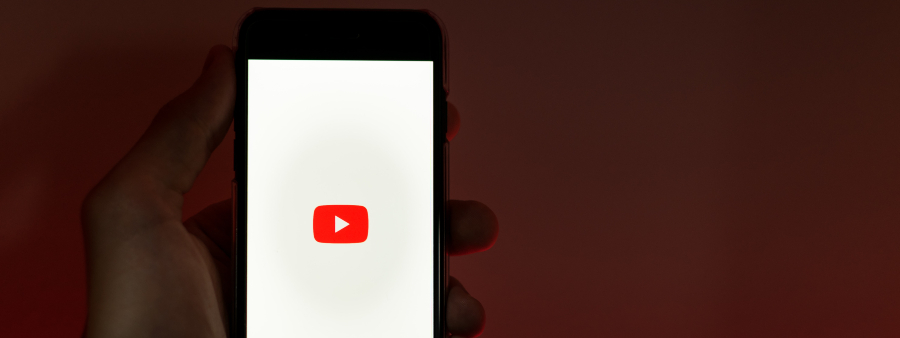 Educação no YouTube: fotografia de uma mão segurando um celular com a marca do YouTube na tela.