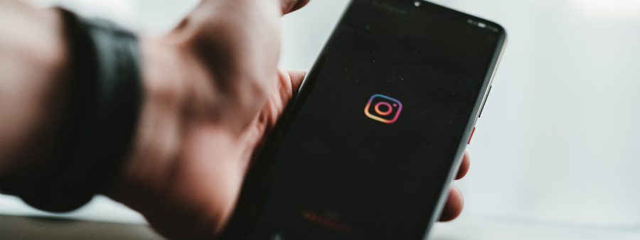 Instagram sobre educação: fotografia com foco na mão de uma pessoa segurando um celular com a marca do Instagram.