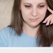 Qual curso escolher: fotografia de uma mulher pensativa olhando para um computador