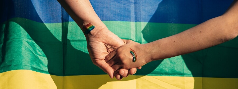 dia do orgulho: mãos dadas em frente à bandeira LGBTQIAP+