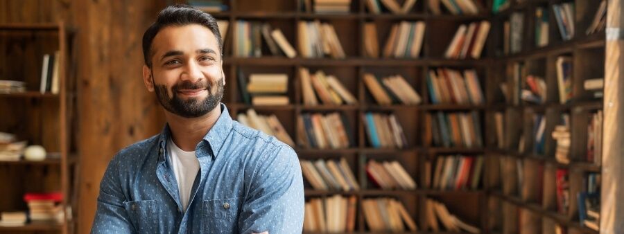 atividades extracurriculares: homem sorrindo em biblioteca