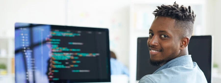 competência tecnológica: homem sorrindo em frente a computador